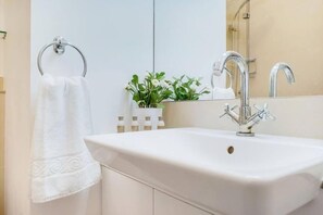 Une salle de bain avec un lavabo blanc, un miroir et un porte-serviettes.