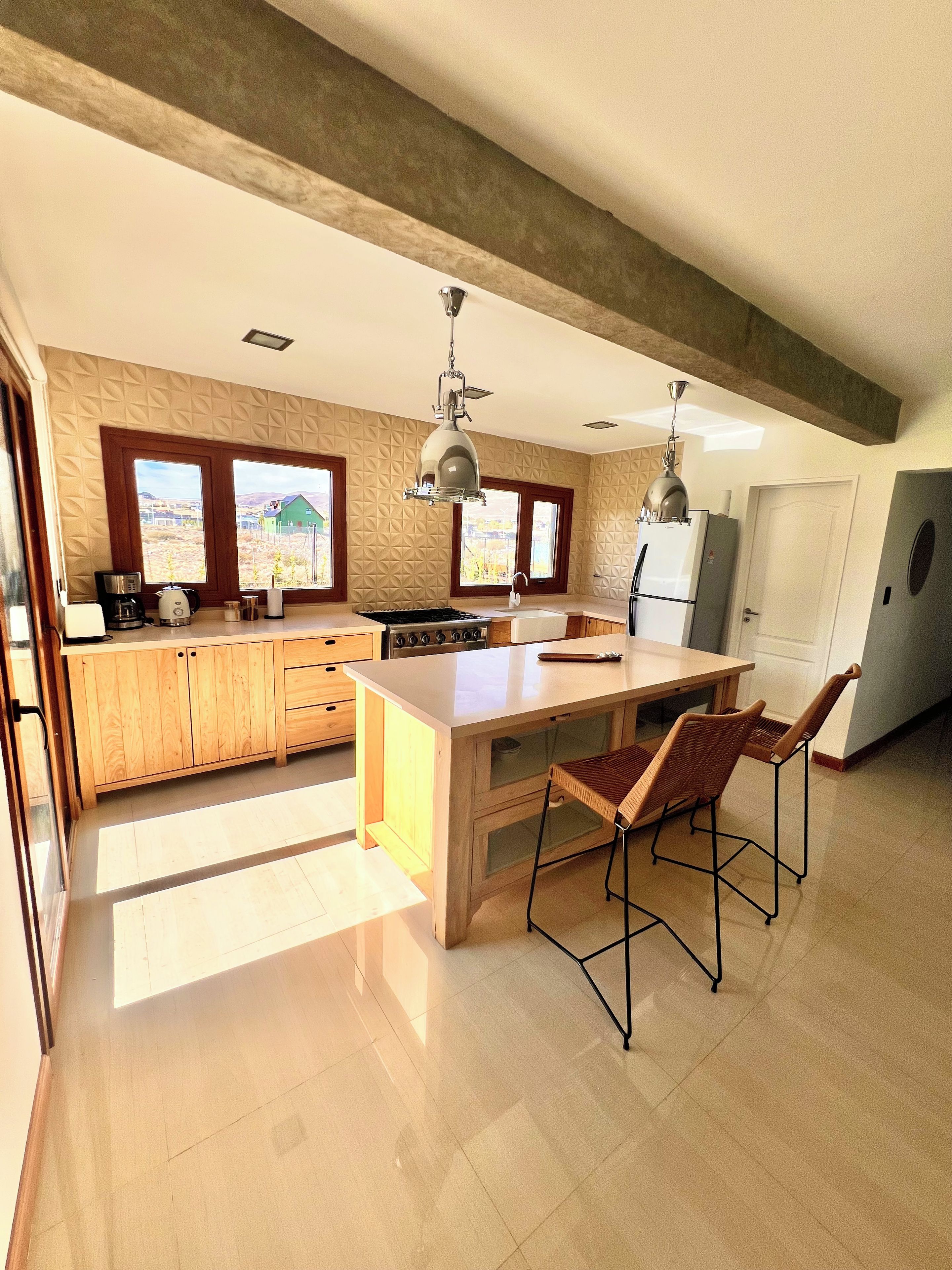 Een moderne keuken met houten kastjes, een centraal eiland en barstoelen.