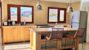 Una cocina moderna con una isla central, armarios de madera y dos ventanas con vistas al paisaje.