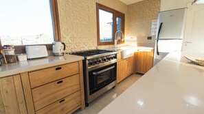 A modern kitchen with a built-in oven, a stovetop, and wooden cabinetry.