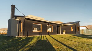 A modern two-story house with a flat roof, large windows, and a chimney.