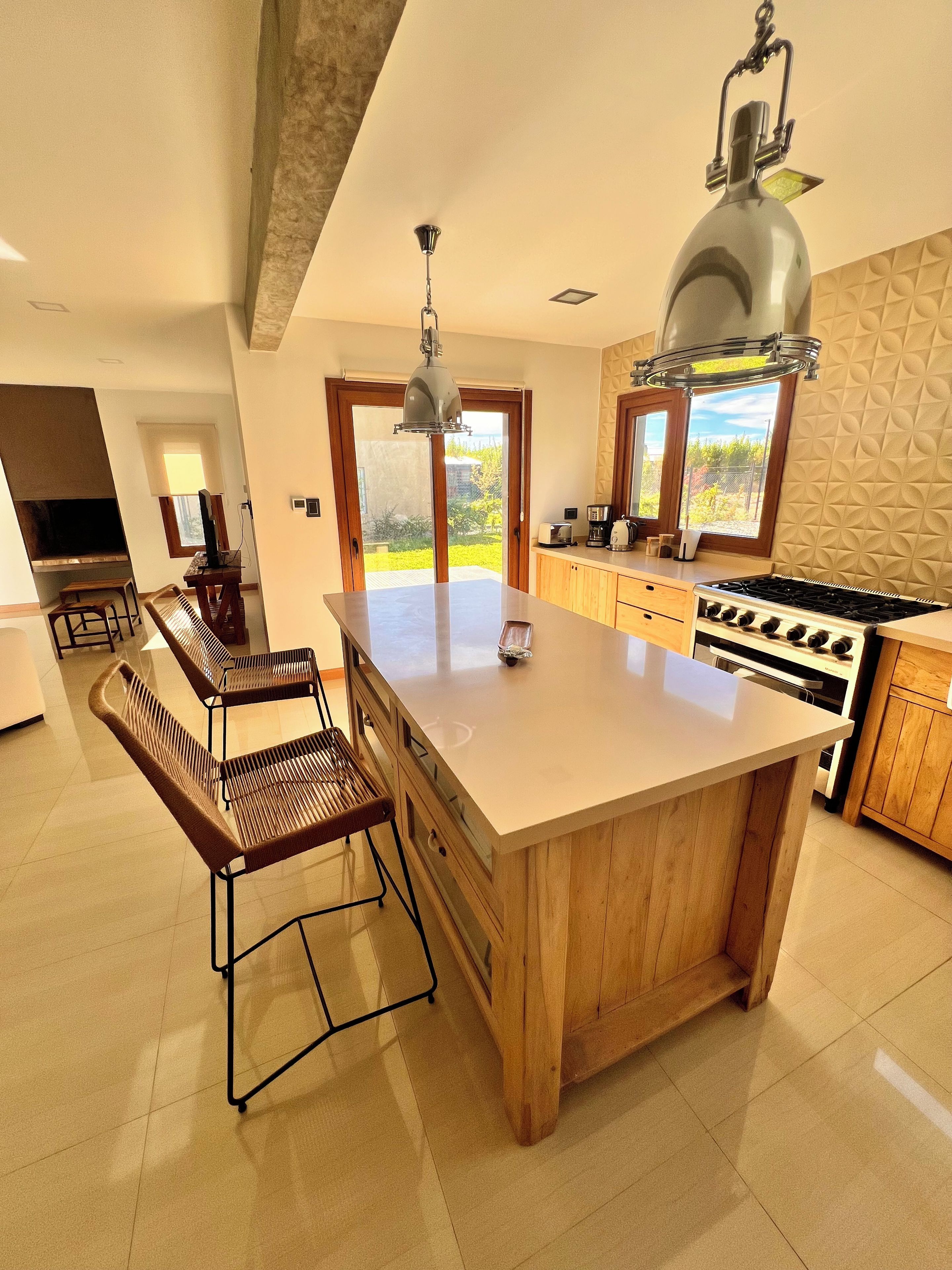 A modern kitchen with a large island, wooden cabinets, and a gas stove.