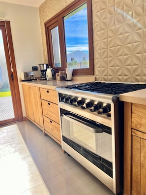 Una cocina con estufa, horno y ventana con vistas al exterior.