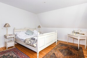 Quarto com uma cama de solteiro, duas mesas de cabeceira, uma escrivaninha e uma cadeira.