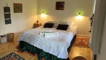 A bedroom with a bed, two wall-mounted lamps, a nightstand, a woven basket, and a patterned rug.