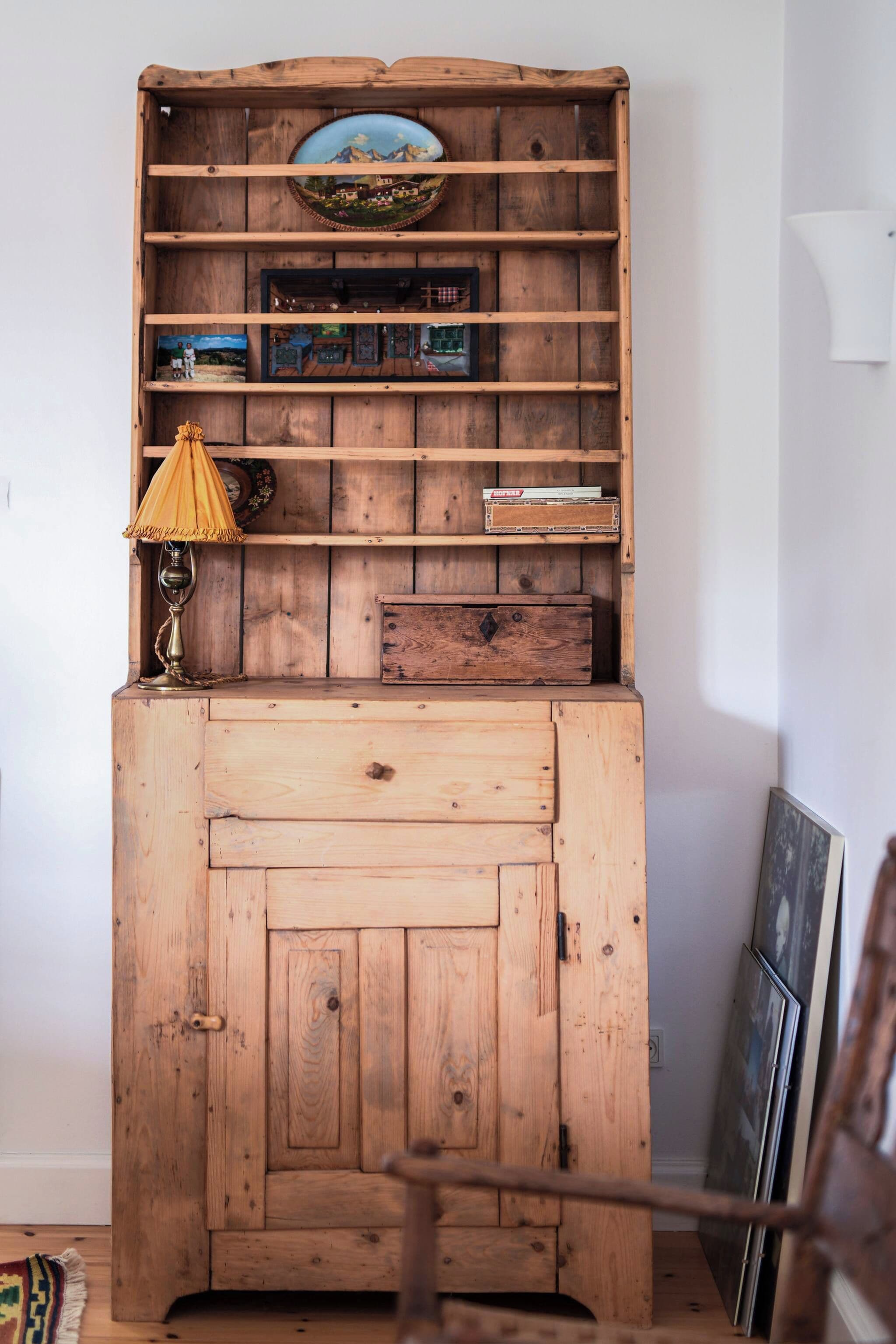 A wooden cabinet with multiple shelves, a lamp, and a framed picture.