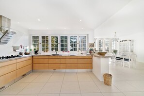 A modern kitchen with a central island, white cabinetry, and large windows.
