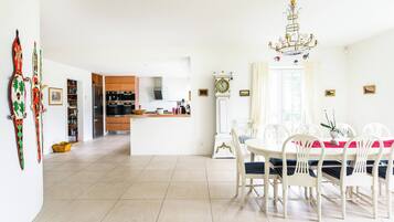 Una cocina amplia con electrodomésticos modernos, un comedor con candelabro y un reloj grande en la pared.