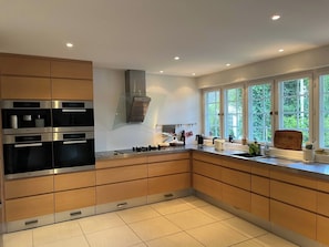 Una cocina moderna con electrodomésticos integrados, un amplio ventanal y vistas al verdor.