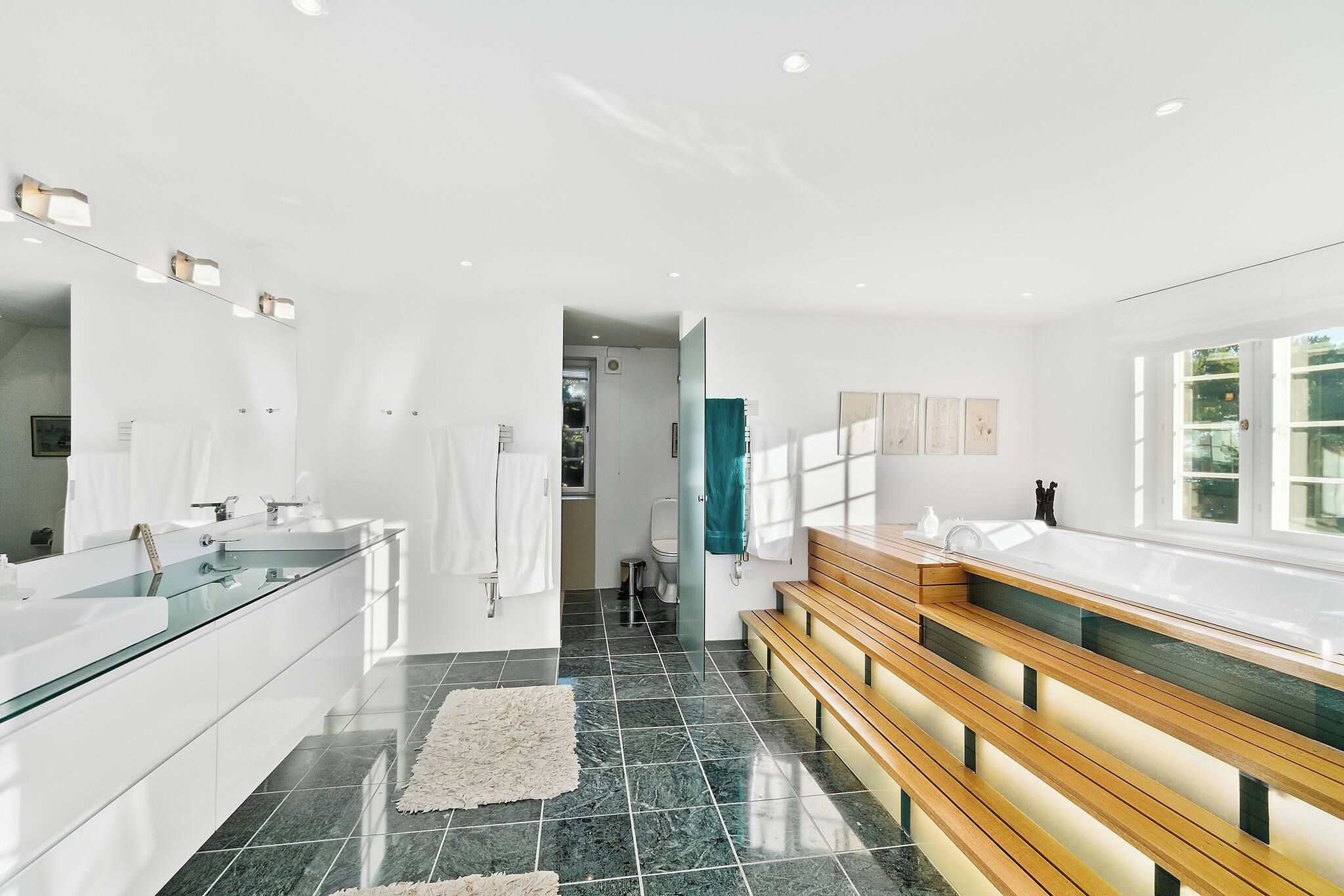 Un baño moderno con cabina de ducha de vidrio, tocador de madera y un espejo grande.
