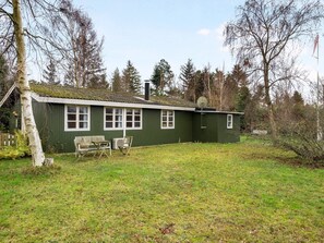 A green single-story house with a fenced yard, a bench, and a satellite dish. - 4 Star Holiday Home in Idestrup (Idestrup)