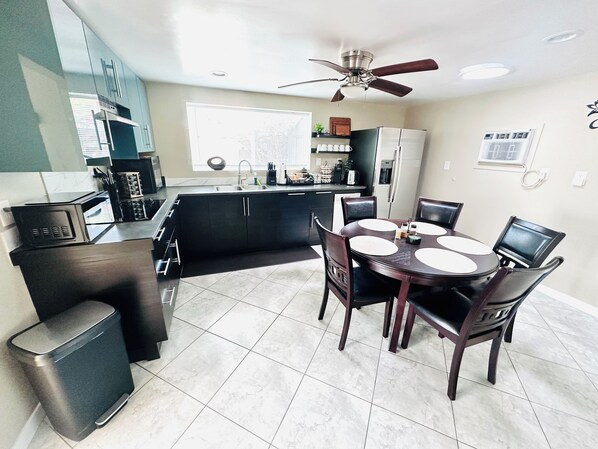 A modern kitchen with a dining area, including a round table with chairs, a ceiling fan, and a refrigerator. - Zen Retreat 3BD Near Lake Murray + SDSU with Gazebo (La Mesa)