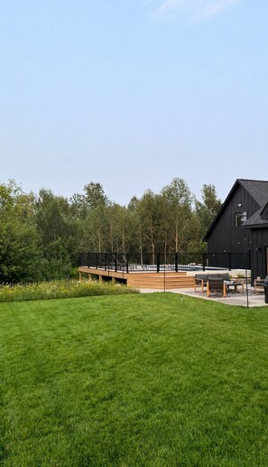 Een modern gebouw met een plat dak, omringd door een verzorgd gazon en een houten terras.