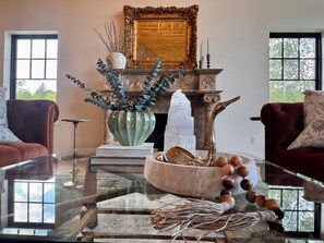 Un salon avec une cheminée, un grand miroir et une table basse en verre.