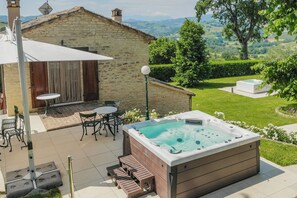 A hot tub in a backyard with a stone building, outdoor furniture, and a view of the countryside. - VILLA ANNA: HEATED POOL, 2 OUTDOOR HOT TUBS, SAUNA, AND GYM (Sant'Ippolito)