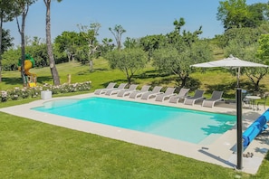 A swimming pool with lounge chairs and a slide, surrounded by greenery. - VILLA ANNA: HEATED POOL, 2 OUTDOOR HOT TUBS, SAUNA, AND GYM (Sant'Ippolito)