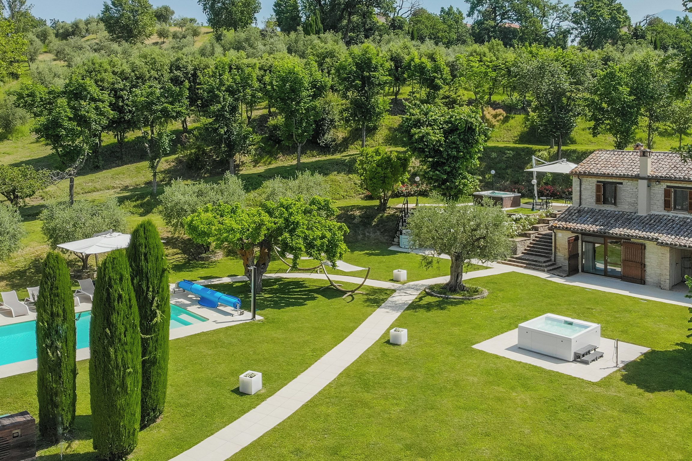 Uma vila com piscina, banheira de hidromassagem e jardim com caminho.