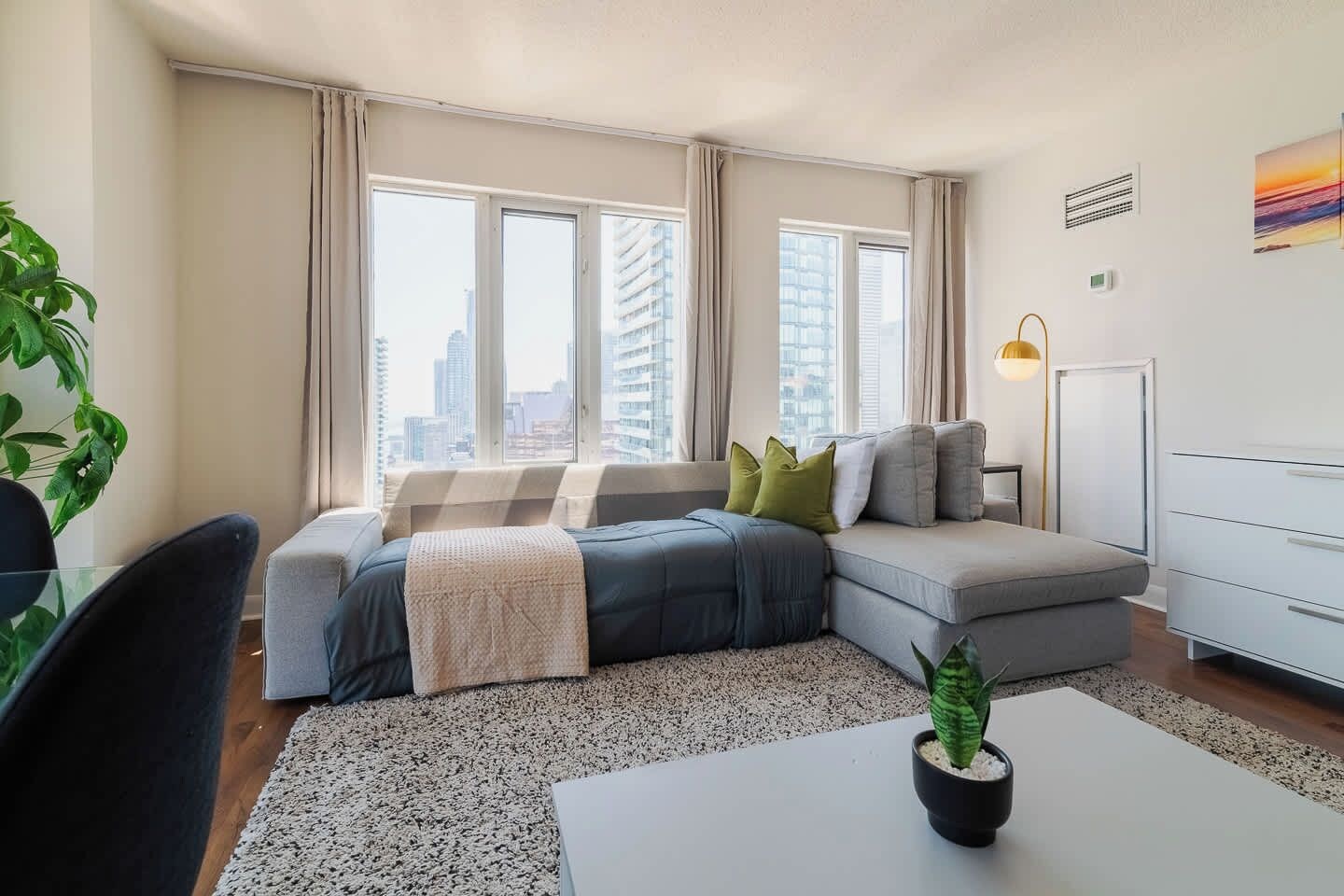 A modern living room with a sectional sofa, a small table, and a potted plant.