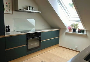 Eine Küche mit eingebautem Backofen, einem Fenster mit Blumentöpfen und einem erhöhten Regal.
