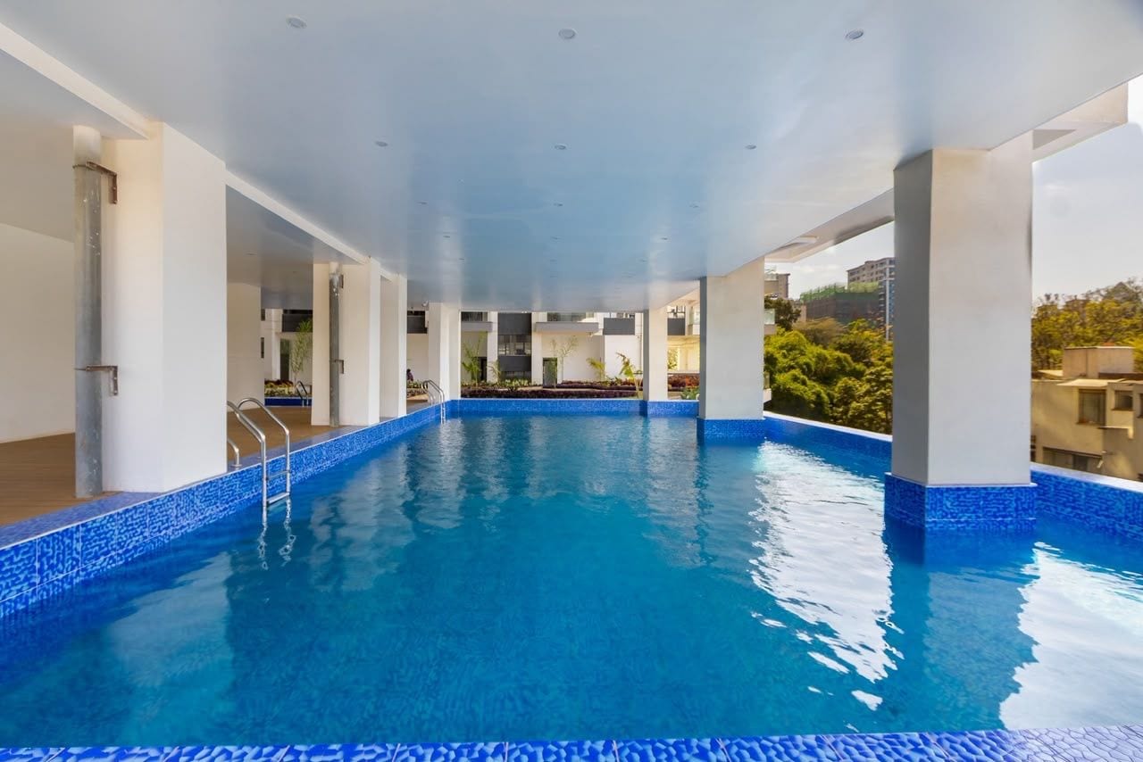 Una piscina interior con agua cristalina, rodeada de pilares blancos y un borde alicatado.