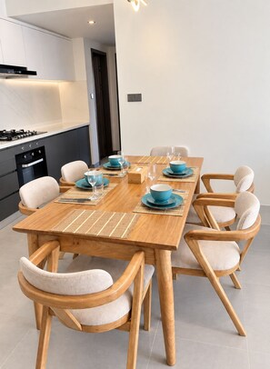 A modern dining area with a wooden table set for six, surrounded by six upholstered chairs. - Chic 2BR with HeatedPool, Gym, Sauna, SteamRoom, Wi-fi , Safe Parking (Nairobi)