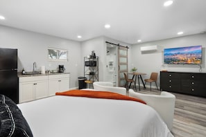 Une chambre d’hôtel équipée d’un lit, d’un bureau, d’une chaise, d’une petite table, d’une télévision et offrant une vue sur la ville.