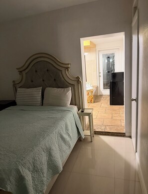 A bedroom with a bed, a nightstand, and a door leading to a balcony. - Cozy Private entrance 1-bedroom in charming  2 Miles Away from Sunny Isles Beach (North Miami Beach)