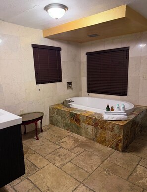 A bathroom with a marble tub, a vanity, a small table, and two windows with blinds. - Cozy Private entrance 1-bedroom in charming  2 Miles Away from Sunny Isles Beach (North Miami Beach)