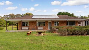 Ein zweistöckiges Haus mit überdachter Veranda, Ziegelaußenwand und Solardach.