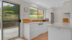 A modern kitchen with a large window, white cabinetry, and a built-in dishwasher. - Bawley Point Coastal Acreage - Guest Retreat (Bawley Point)