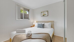 A bedroom with a bed, a window, a bedside table, and a wall-mounted artwork. - Bawley Point Coastal Acreage - Guest Retreat (Bawley Point)