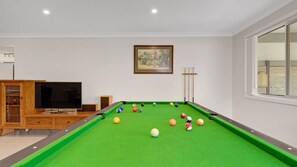 Ein Zimmer mit Pooltisch, Fernseher und einem gerahmten Bild an der Wand.
