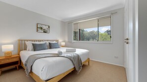 Ein Schlafzimmer mit einem Bett, Nachttischlampen, einem Fenster und einer Tür.