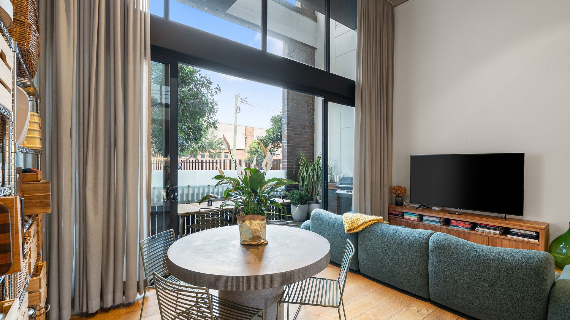 A modern living room with a round table, a sofa, a television, and a view of the outside.
