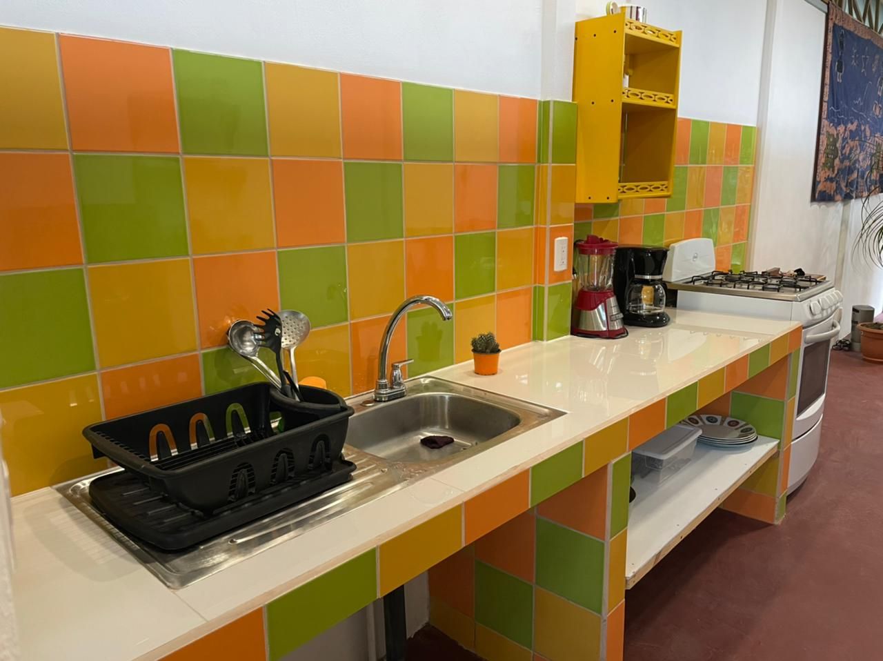 Een keuken met een kleurrijke tegelachtergrond, een spoelbak, een fornuis en een koffiezetapparaat.
