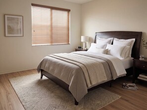 A neatly arranged bedroom with a bed, bedside tables, a lamp, and a window with blinds. - Modern Palm Coast Oasis with Private Pool (Palm Coast)