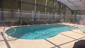 A swimming pool with a metal ladder, surrounded by a covered patio area with chairs. - Modern Palm Coast Oasis with Private Pool (Palm Coast)