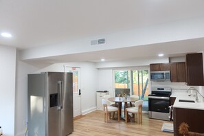 A modern kitchen with a refrigerator, stove, microwave, and dining area with chairs. - Peaceful 5-bedroom house with AC in beautiful Lynnwood (Lynnwood)