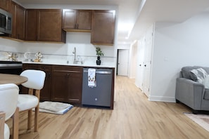 A modern kitchen with wooden cabinets, a stainless steel refrigerator, and a dining area with a white table and chairs. - Peaceful 5-bedroom house with AC in beautiful Lynnwood (Lynnwood)