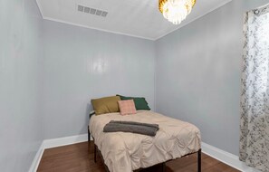 Ein Schlafzimmer mit Bett, einer Chandelier und einem Fenster mit Vorhängen.