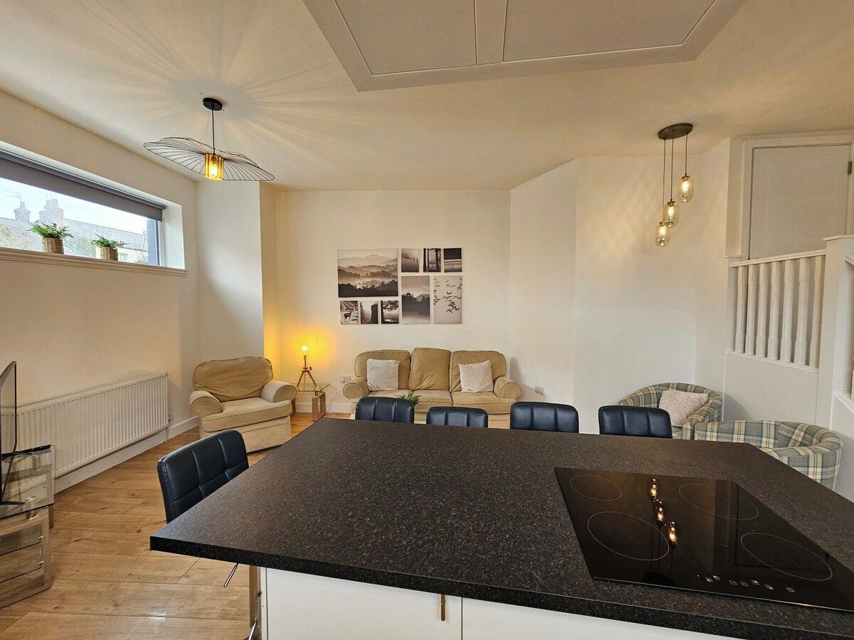 A modern kitchen with a central island, a dining area with a table and chairs, and a living area with a sofa and a coffee table.