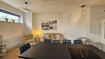 A modern kitchen with a central island, a dining area with a table and chairs, and a living area with a sofa and a coffee table.