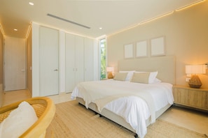 Ein modernes Schlafzimmer mit einem großen Bett, einem Holznachttisch, einem Korbstuhl und einem großen Fenster.
