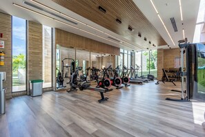 Ein modernes Fitnessstudio mit verschiedenen Trainingsgeräten, großen Fenstern und einer Holzboden.