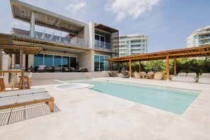 Ein moderner Poolbereich im Freien mit Liegestühlen und einer Pergola.