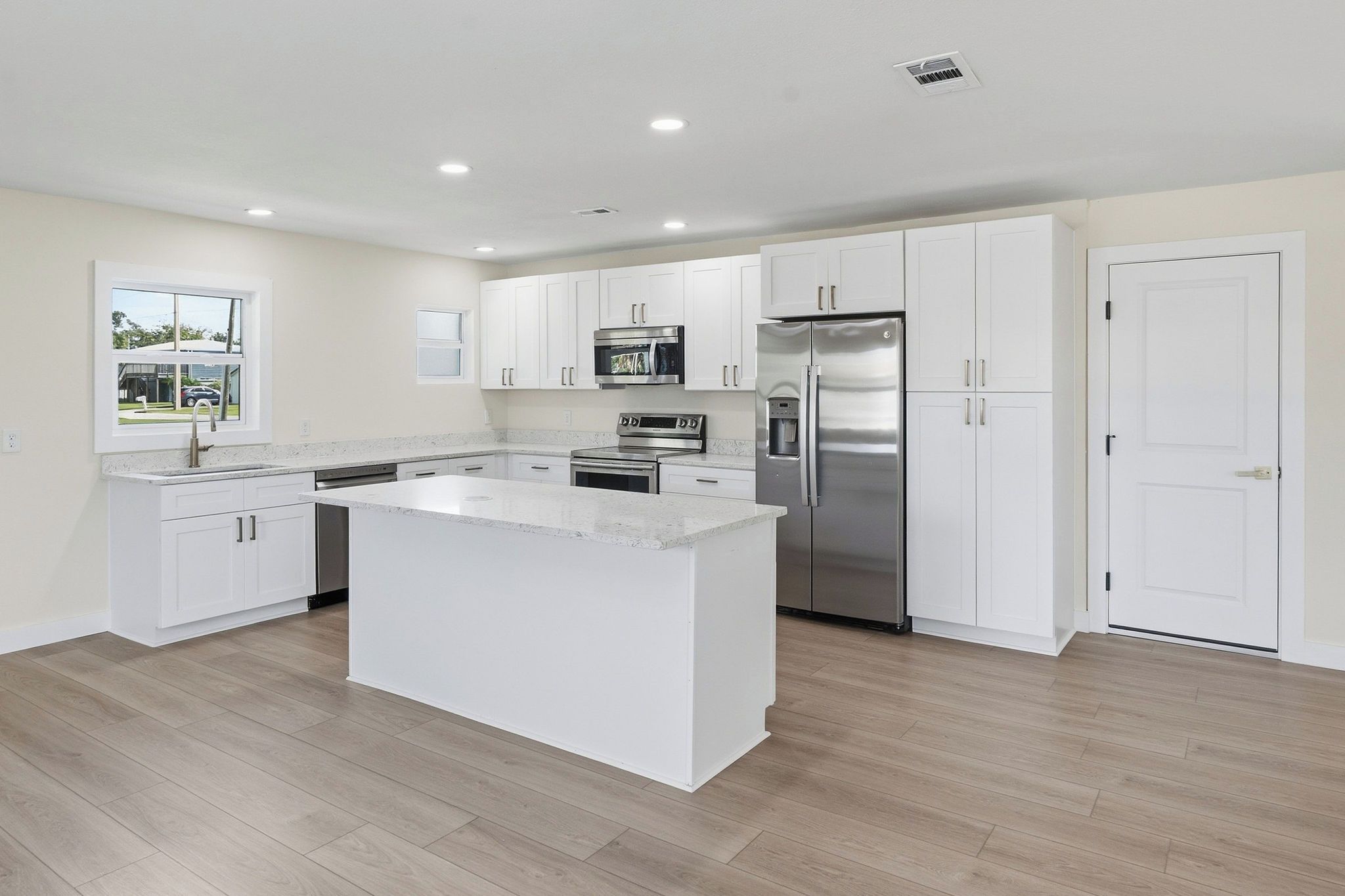 A modern kitchen with white cabinetry, stainless steel appliances, and a central island.