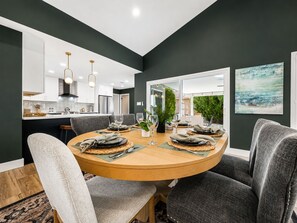 A modern dining area with a round table set for six, surrounded by grey upholstered chairs. - Beech Creek Sun Lakes (Chandler)