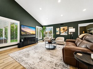 A modern living room with a flat-screen TV, leather sofa, and a coffee table. - Beech Creek Sun Lakes (Chandler)