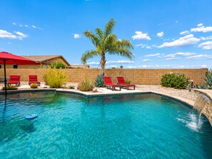 A clear blue pool with red lounge chairs and a palm tree. - Amazing Views for Miles! Oro Valley Stunner (Oro Valley)
