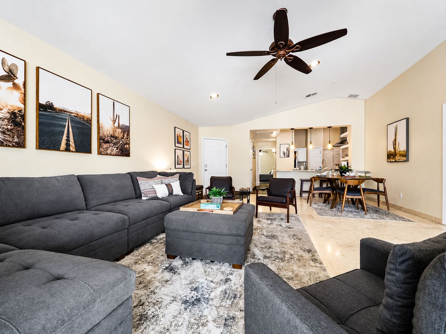 A modern living room with a grey sofa, a coffee table, and a ceiling fan.